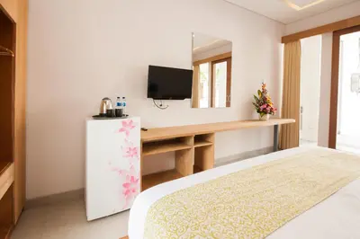a bedroom with a bed and a desk with a television at Apple Villa & Suite Seminyak in Seminyak