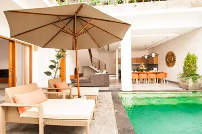 a patio with an umbrella and a swimming pool at Apple Villa & Suite Seminyak in Seminyak