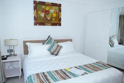 a bedroom with a white bed and a picture on the wall at Sofi Apartment at Jayakarta Residence in Legian