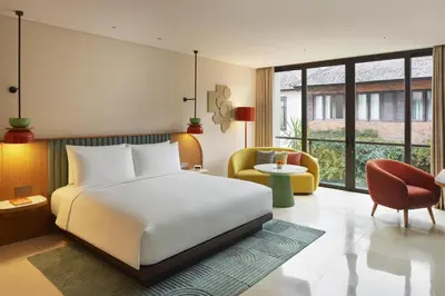 a bedroom with a large white bed and a chair at Kleo Seminyak, part of JdV by Hyatt in Seminyak
