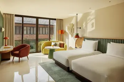 a hotel room with two beds and a chair at Kleo Seminyak, part of JdV by Hyatt in Seminyak