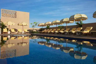 a swimming pool with umbrellas and lounge chairs and a pool at Kleo Seminyak, part of JdV by Hyatt in Seminyak