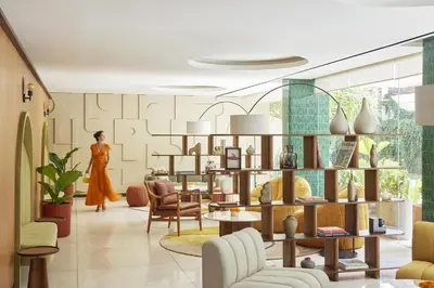 a woman walking through a living room with furniture at Kleo Seminyak, part of JdV by Hyatt in Seminyak