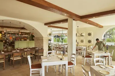 a man standing in a restaurant with tables and chairs at Kleo Seminyak, part of JdV by Hyatt in Seminyak