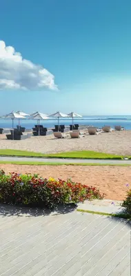 a beach with chairs and tables and umbrellas at Tijili Hotel Benoa in Nusa Dua
