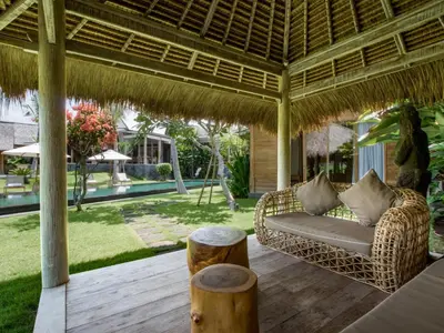 a patio with a couch under a large umbrella at Mannao Estate by Villa Finder in Kerobokan