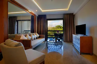 a living room with a couch and a television at Royal Tulip Springhill Resort Jimbaran in Jimbaran
