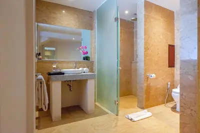 a bathroom with a shower and a sink and a toilet at Royal Tulip Springhill Resort Jimbaran in Jimbaran