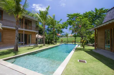 a swimming pool in a yard next to a house at Alea Estate in Kerobokan