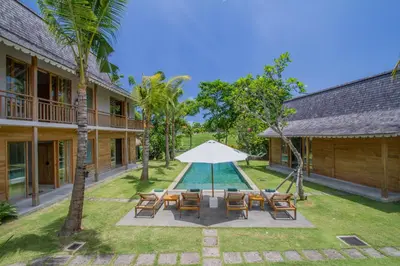 a patio with chairs and an umbrella and a pool at Alea Estate in Kerobokan