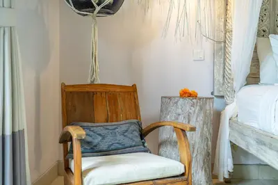 a wooden chair in a room with a bed at Villa Sarong 2 Chic 2BR Boho Villa Prime Central Location in Seminyak