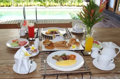 a table with plates of breakfast food on it at Kubu GWK Villa in Jimbaran