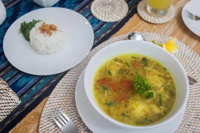 a bowl of soup next to a plate of rice at Kubu GWK Villa in Jimbaran