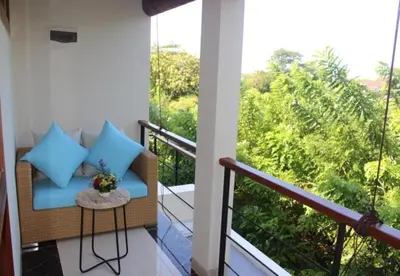a balcony with a couch and a large window at Kubu GWK Villa in Jimbaran