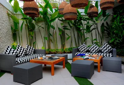 a patio with black and white chairs and tables and plants at Benoa Sea Suites and Villas in Nusa Dua