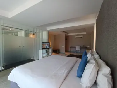 a bedroom with a large white bed with blue pillows at Benoa Sea Suites and Villas in Nusa Dua