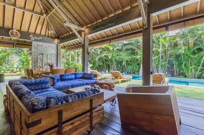 a large living room with blue couches and a pool at Villa Kundalini in Seminyak