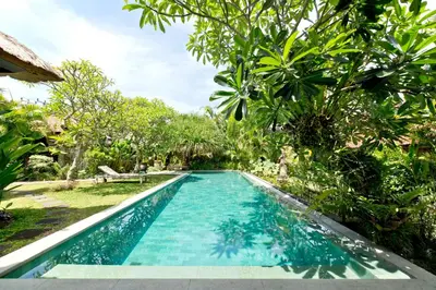 a swimming pool in a garden with trees at Bali Villa Aja in Seminyak