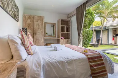 a bedroom with a large bed and a couch at VILLA Nuri Merah 1 in Kerobokan