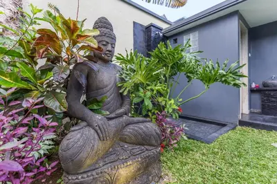 a statue of a woman sitting on a rock in a garden at VILLA Nuri Merah 1 in Kerobokan