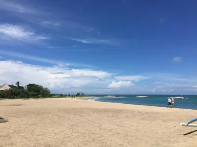 a beach with people walking on the sand and the water at Sulis Beach Hotel & Spa in Kuta