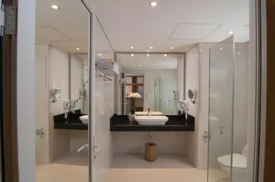 a bathroom with two sinks and a glass shower at Sulis Beach Hotel & Spa in Kuta