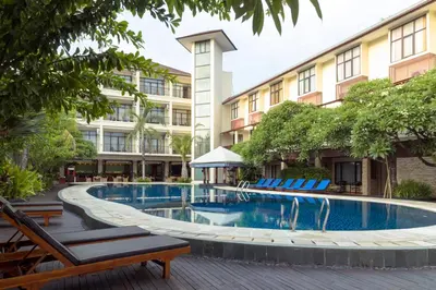 a swimming pool with lounge chairs in front of a building at Best Western Resort Kuta in Kuta
