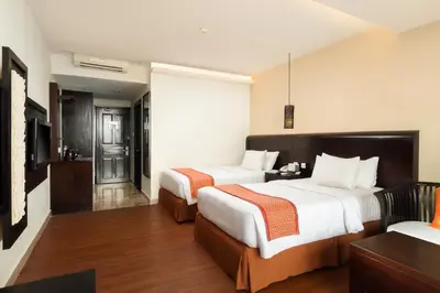 a hotel room with two beds and a television at Best Western Resort Kuta in Kuta