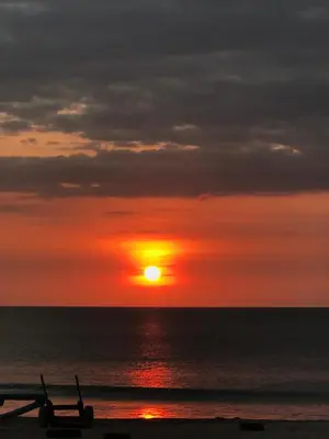 a sunset over the ocean with a plane on the beach at The Celuk Homestay in Jimbaran