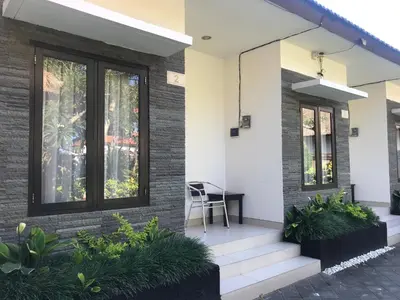 a house with a window and a chair on the porch at The Celuk Homestay in Jimbaran