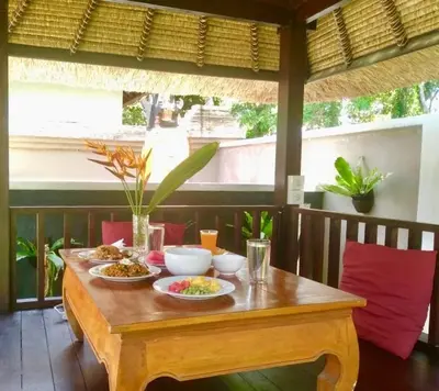 a wooden table with two plates of food on it at The Celuk Homestay in Jimbaran