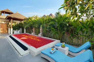 a garden with a pool and two blue chairs at Holl Villa by Wildflower Group in Legian