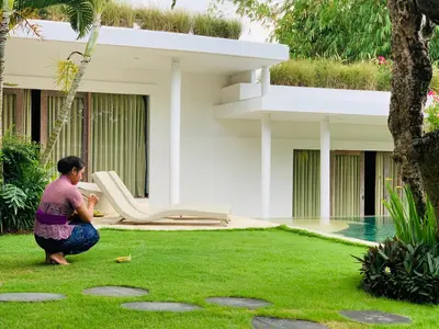 a woman sitting on the grass in front of a house at Villa Anema Umalas in Seminyak