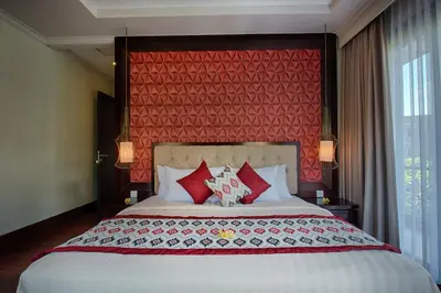 a bedroom with a large bed with a red wall at Natya Villa Jimbaran in Jimbaran