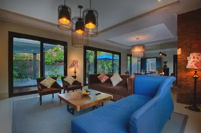 a living room with a blue couch and a table at Natya Villa Jimbaran in Jimbaran