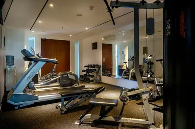 a gym with several tread machines and a mirror at THE HAVEN Bali Seminyak in Seminyak