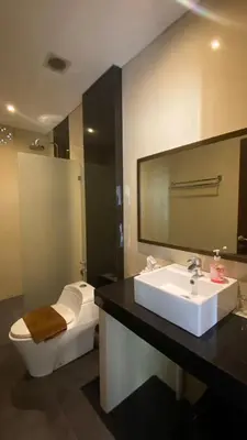 a bathroom with a sink and a toilet and a mirror at The Surya Kuta Villa in Kuta