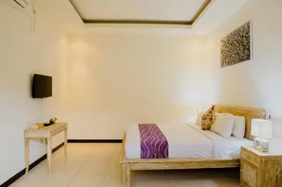 a bedroom with a bed and a tv on a wall at Villa Raka Managed by Manara in Legian