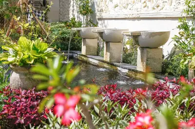 a row of stone sinks in a garden with flowers at Villa La Luvier in Canggu