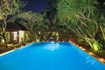 a large swimming pool with blue water at night at Villa La Luvier in Canggu