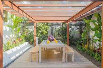 a wooden deck with a table with flowers on it at Villa La Luvier in Canggu