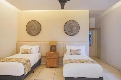 a room with two beds and a table and two mirrors at Villa La Luvier in Canggu