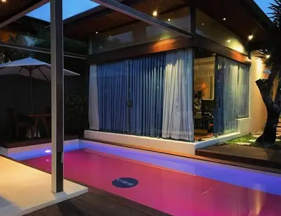 a house with a swimming pool at night at Kiss Bali Villas in Seminyak