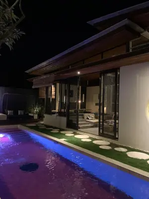a swimming pool in front of a house at night at Kiss Bali Villas in Seminyak