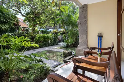 two wooden chairs sitting on the porch of a house at Adhi Jaya Hotel in Kuta