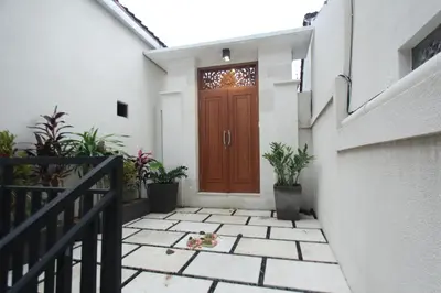a wooden door on a white building with potted plants at Tom Guest House in Legian