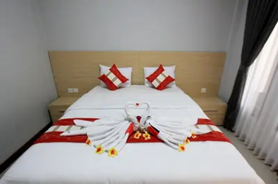 a bedroom with a bed with two swans made out of towels at Tom Guest House in Legian