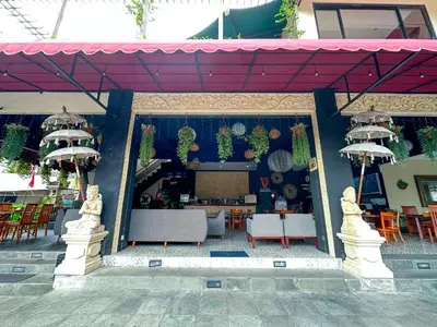 a restaurant with tables and chairs and a red roof at Dekuta in Kuta