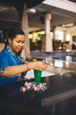 a woman holding a green cup with flowers in it at The Niche Bali in Legian