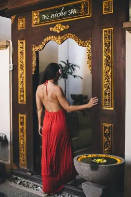 a woman in a red dress looking into a mirror at The Niche Bali in Legian
